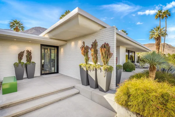 a living room with patio furniture and a potted plants