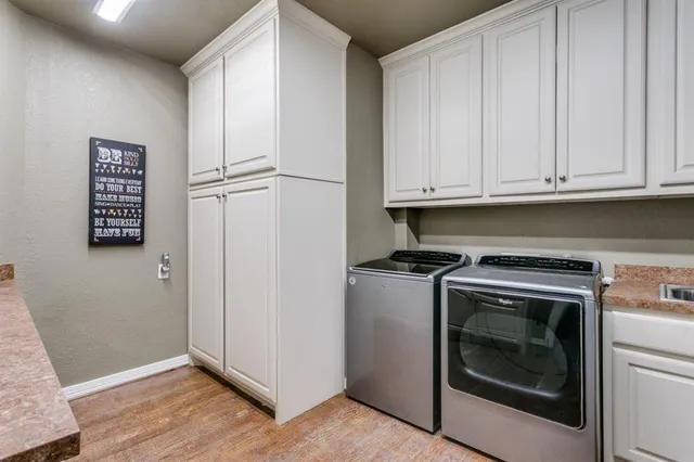 a kitchen with stainless steel appliances granite countertop a refrigerator a sink dishwasher a stove and white cabinets with wooden floor