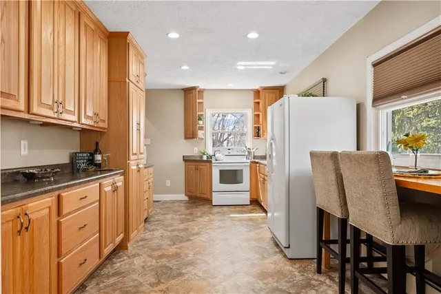 a kitchen with stainless steel appliances granite countertop a refrigerator a stove a sink a dining table and chairs with wooden floor