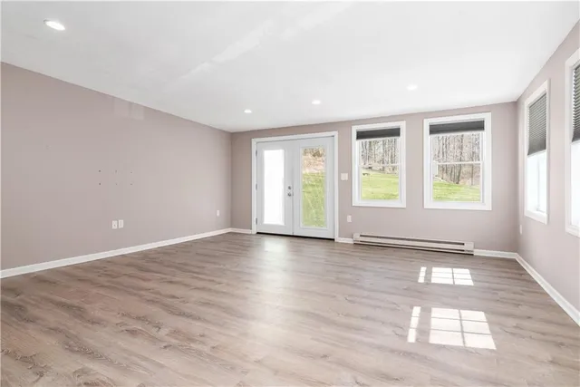 an empty room with wooden floor and windows