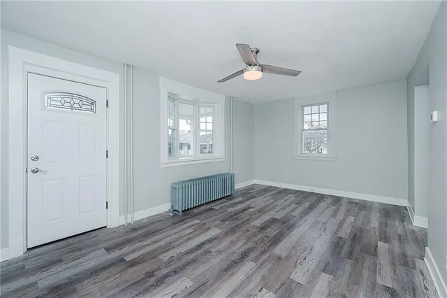 a view of an empty room with wooden floor and a window