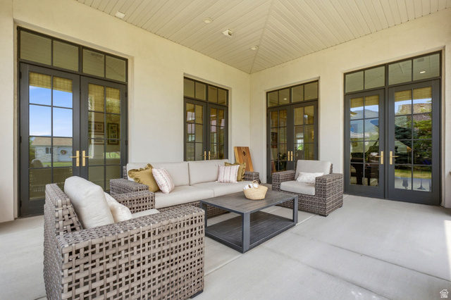 71 Farm Road Midway, UT 84049 - Photo 86 of 92 Covered patio featuring a slatted ceiling, light-toned concrete flooring, and multiple sets of black-framed French doors with transom windows and brass hardware