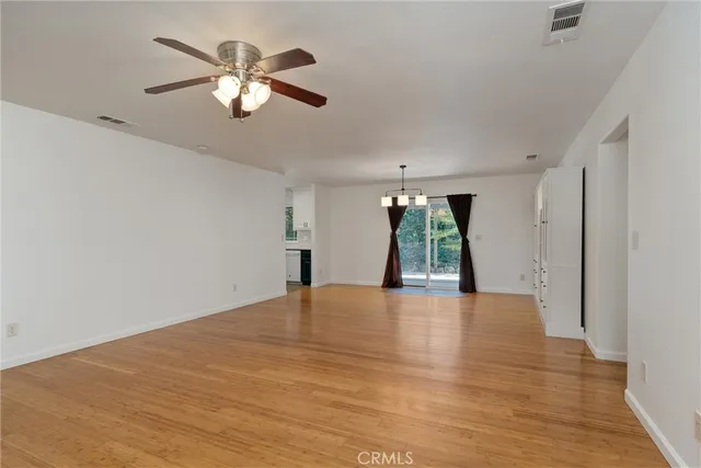 an empty room with chandelier fan and windows