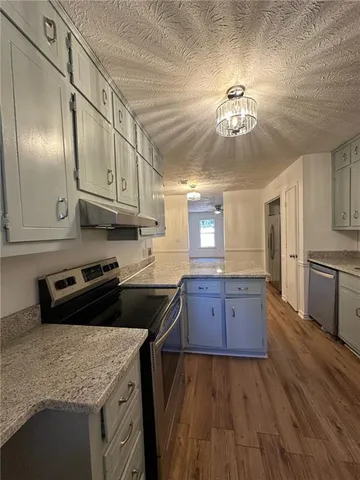 a kitchen with granite countertop a stove cabinets and wooden floor