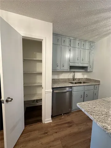 a kitchen with kitchen island granite countertop a sink cabinets and stainless steel appliances
