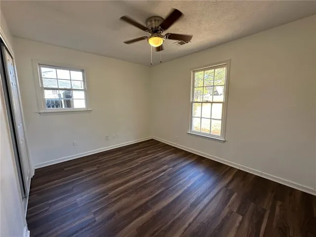 a view of an empty room with window and wooden floor