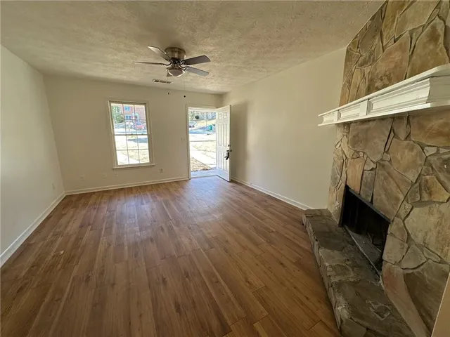 a view of a livingroom with wooden floor a ceiling fan and windows