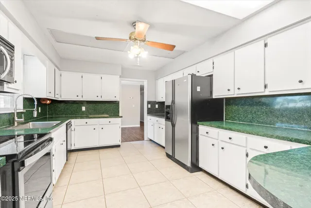 a kitchen with granite countertop a refrigerator oven a sink dishwasher and white cabinets