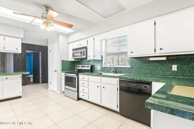 a kitchen with stainless steel appliances granite countertop a sink and dishwasher a stove top oven with white cabinets