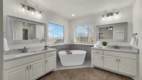 a bathroom with a double vanity sink a mirror a bathtub and window