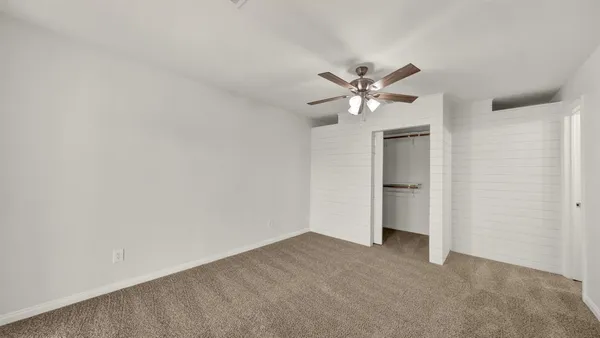 an empty room with chandelier fan