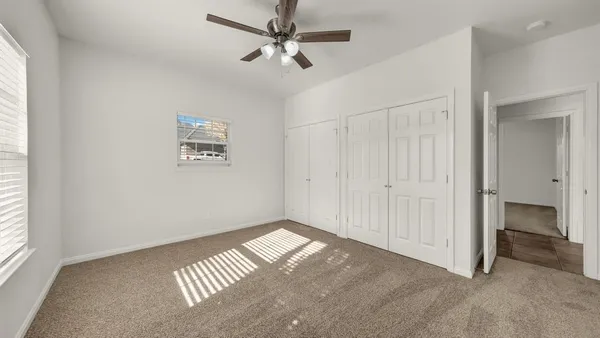 an empty room with windows and fan
