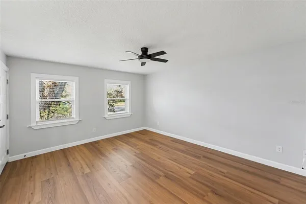 an empty room with wooden floor and windows