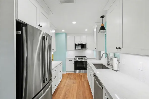 a kitchen with stainless steel appliances a refrigerator sink and white cabinets