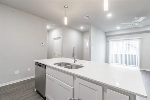 a kitchen with a sink and dishwasher with wooden floor