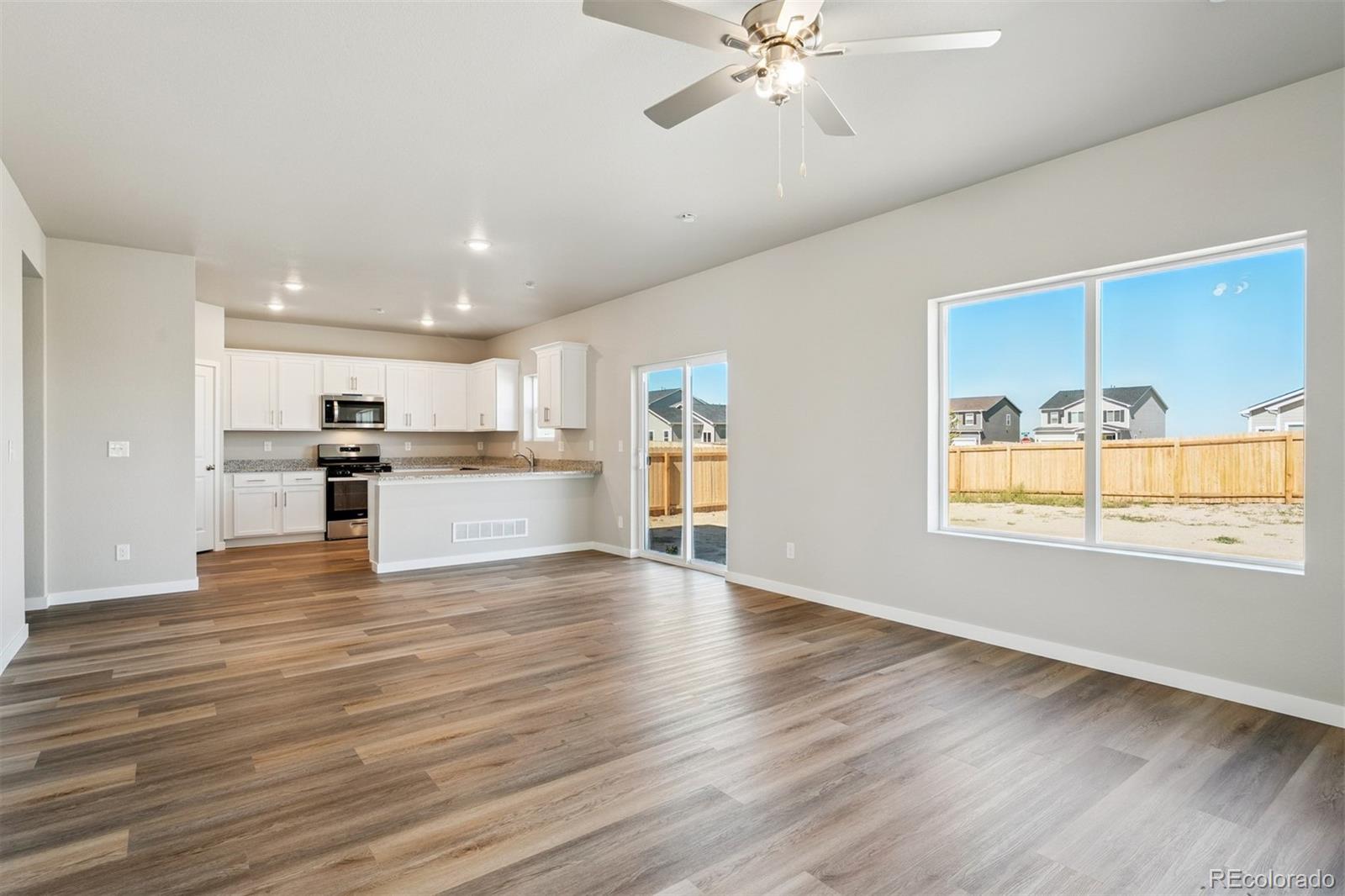 2125 Alyssa Street Fort Lupton, CO 80621 - Photo 5 of 39 a view of an empty room with wooden floor and a window