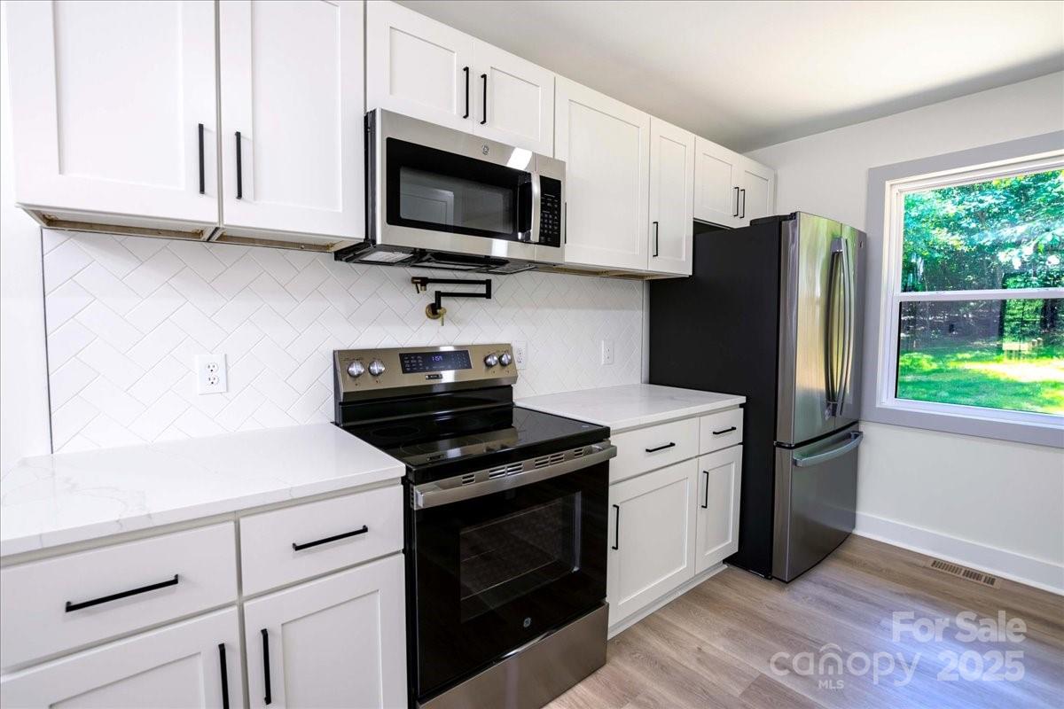 2918 Lon Street Shelby, NC 28152 - Photo 9 of 17 a kitchen with stainless steel appliances white cabinets a stove a microwave and a refrigerator