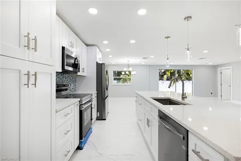a large kitchen with stainless steel appliances kitchen island granite countertop a sink and cabinets