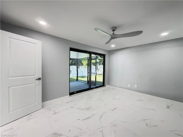 an empty room with windows and ceiling fan