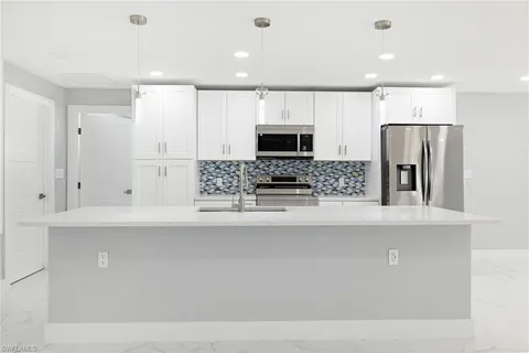 a kitchen with stainless steel appliances a refrigerator sink and microwave