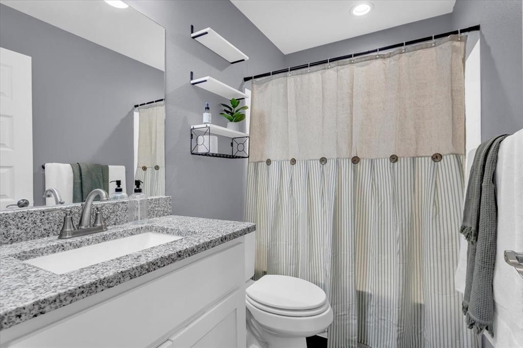 312 East Day Street Denison, TX 75021 - Photo 16 of 24 a bathroom with a granite countertop sink and a mirror