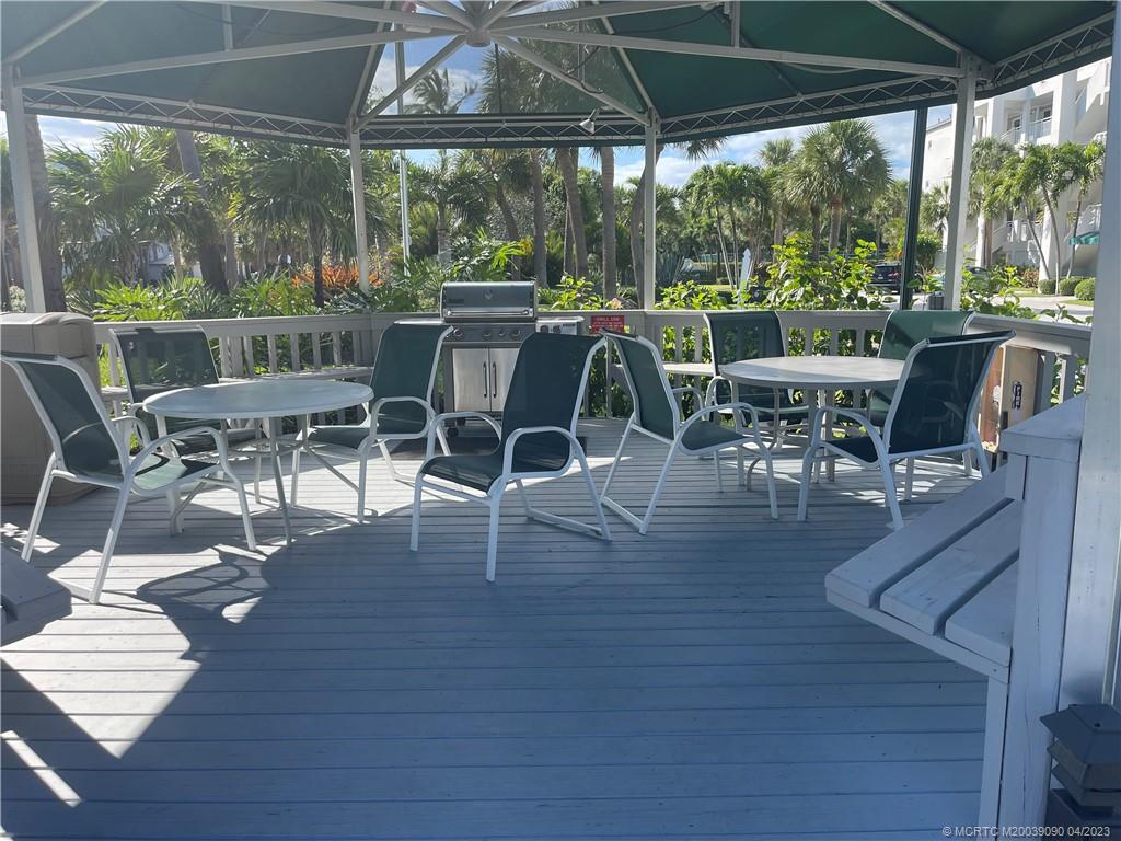 144 Northeast Edgewater Drive, Unit 3102 Stuart, FL 34996 - Photo 19 of 23 a view of a patio with table and chairs potted plants with wooden floor and fence