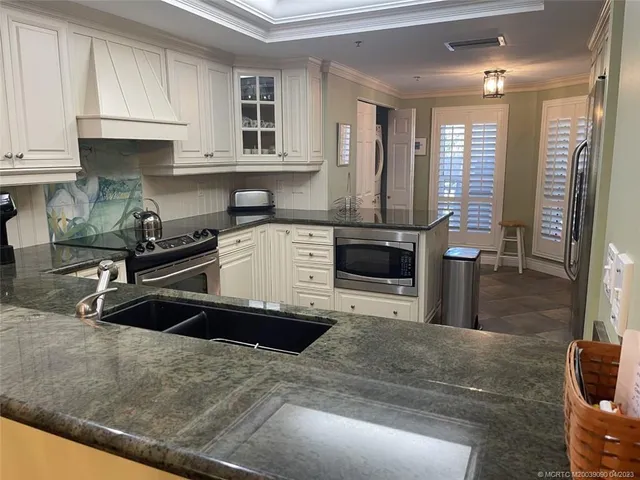 a kitchen with granite countertop a sink a stove and cabinets