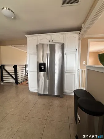 a view of a refrigerator in kitchen and an empty room