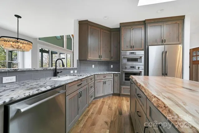 a kitchen with stainless steel appliances granite countertop a refrigerator a stove and a wooden floors