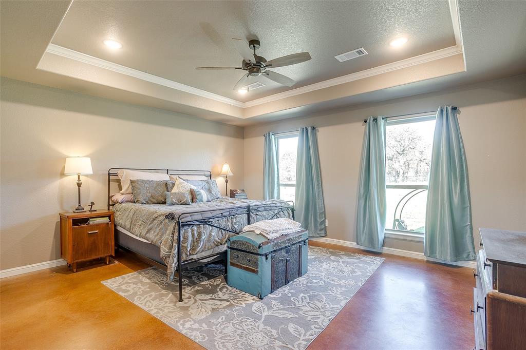 1028 Hope Court Boyd, TX 76023 - Photo 22 of 40 a spacious bedroom with a bed and a chandelier