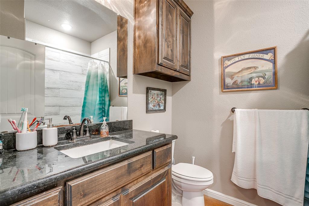 1028 Hope Court Boyd, TX 76023 - Photo 32 of 40 a bathroom with a granite countertop toilet sink and mirror