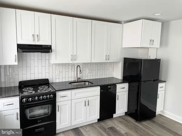 a kitchen with white cabinets and black appliances