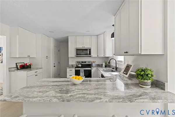 a kitchen with stainless steel appliances granite countertop a sink a stove and white cabinets