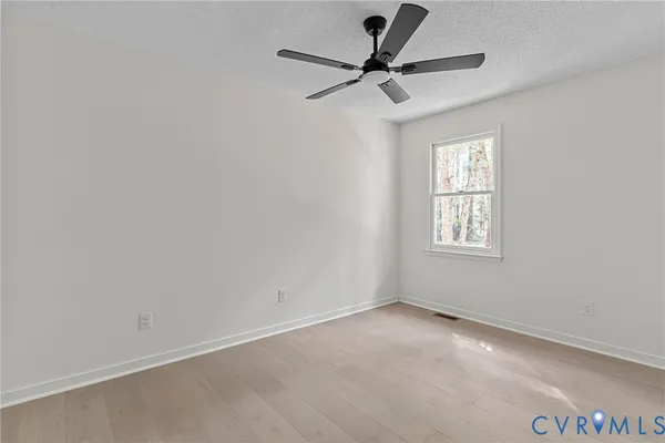 an empty room with a window and a fan