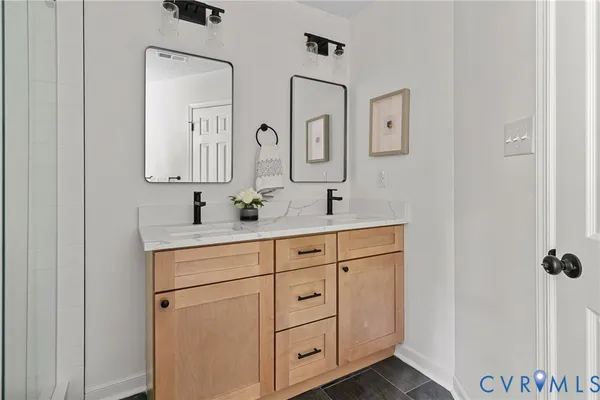 a bathroom with double vanity sink two mirror and window