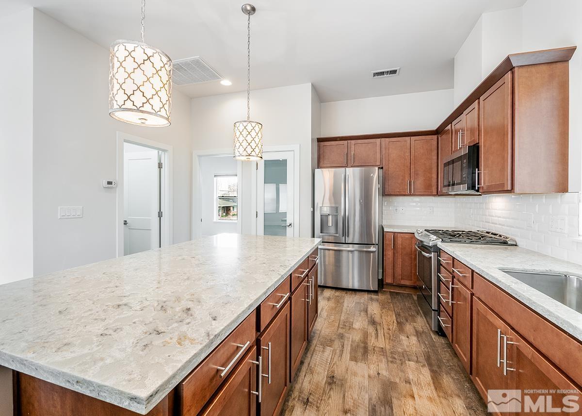 500 Sinclair Street Reno, NV 89501 - Photo 17 of 24 a kitchen with stainless steel appliances granite countertop a refrigerator a sink dishwasher a stove and white countertops with wooden floor