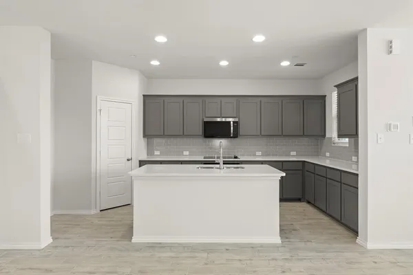 a large kitchen with stainless steel appliances granite countertop a stove a sink a refrigerator and a granite counter tops with wooden floors