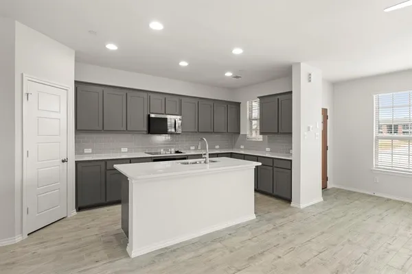 a kitchen with stainless steel appliances granite countertop a stove top oven a sink and a refrigerator