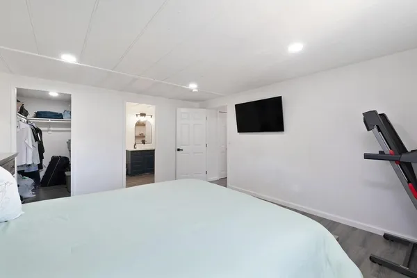 a bedroom with a bed and a flat tv screen on wall