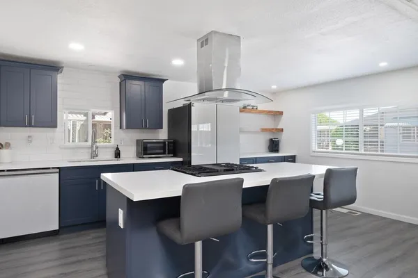a kitchen with stainless steel appliances a dining table chairs refrigerator and sink