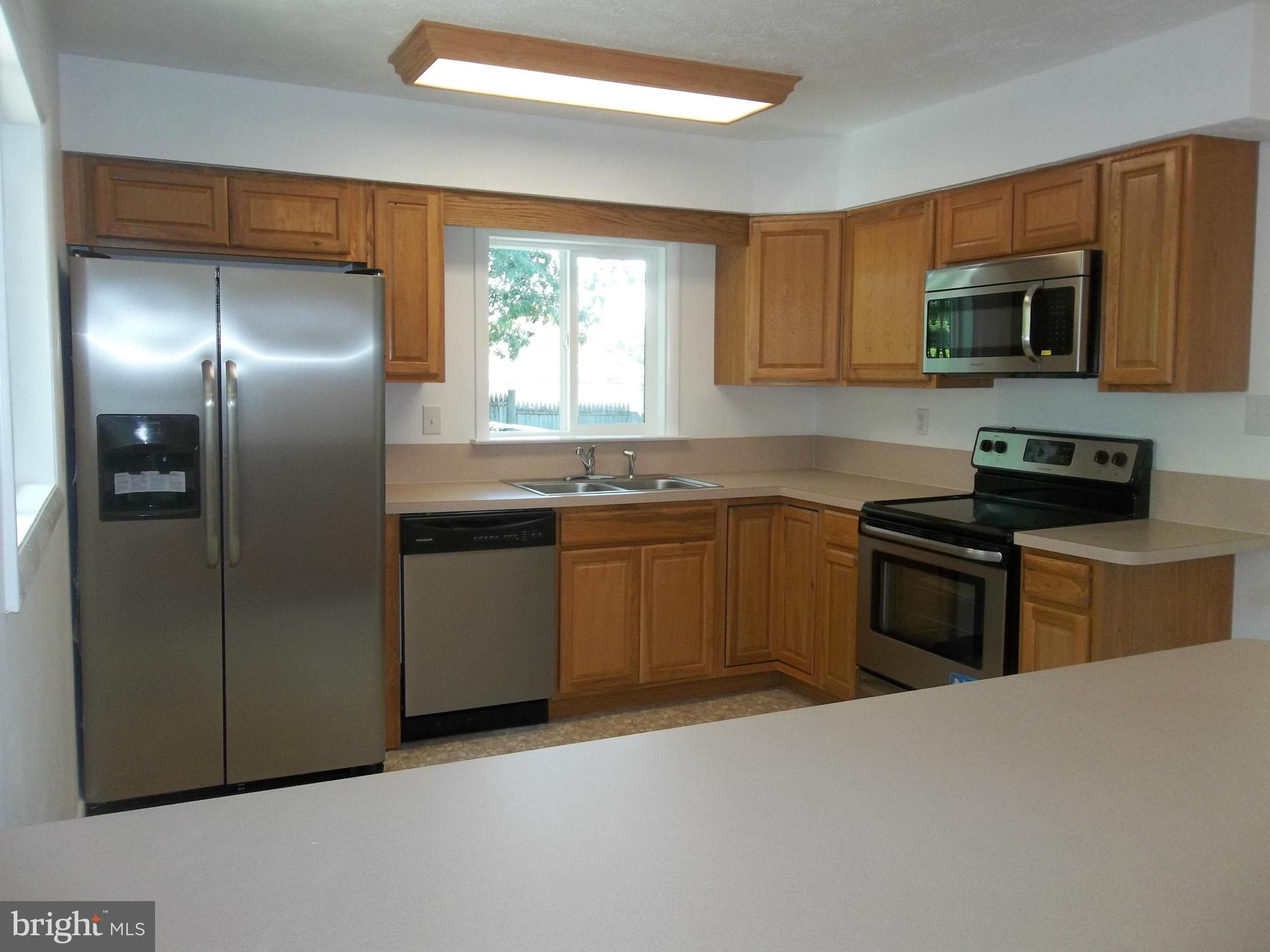 6038 Howellsville Road Front Royal, VA 22630 - Photo 16 of 30 a kitchen with stainless steel appliances granite countertop a refrigerator a sink a stove a microwave and wooden cabinets