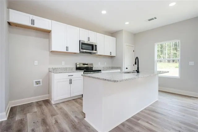 a kitchen with stainless steel appliances granite countertop a sink a stove a microwave and cabinets