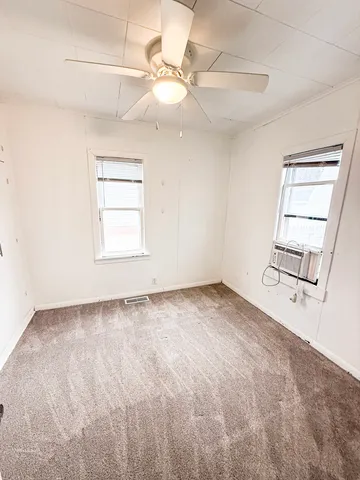 an empty room with windows and fan