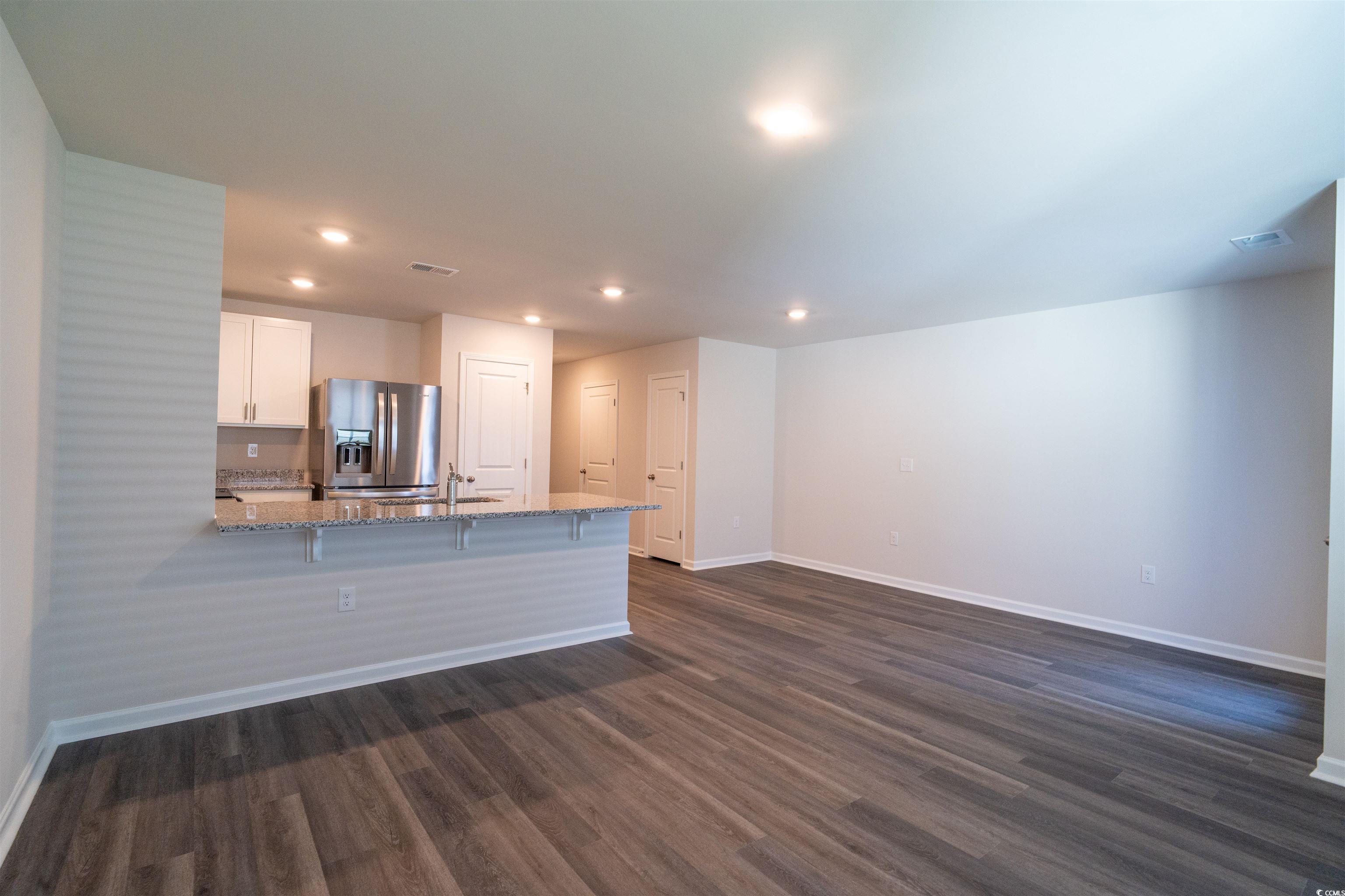 160 Harvest Gold Drive Conway, SC 29526 - Photo 7 of 37 Kitchen featuring white cabinetry, light stone countertops, a peninsula, stainless steel fridge, and a breakfast bar area