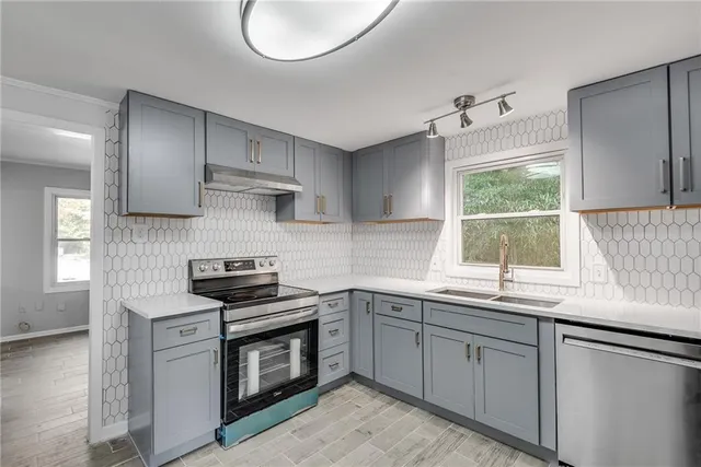 a kitchen with stainless steel appliances granite countertop a sink a stove and a window