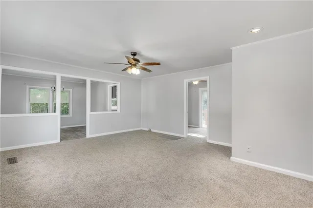 a view of an empty room with chandelier fan
