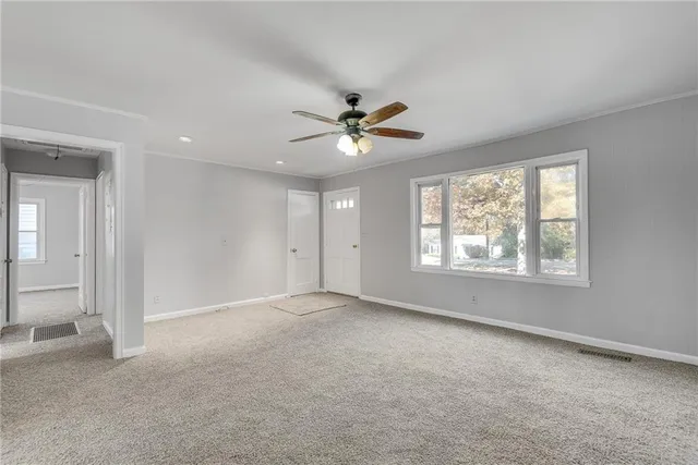 an empty room with windows and fan