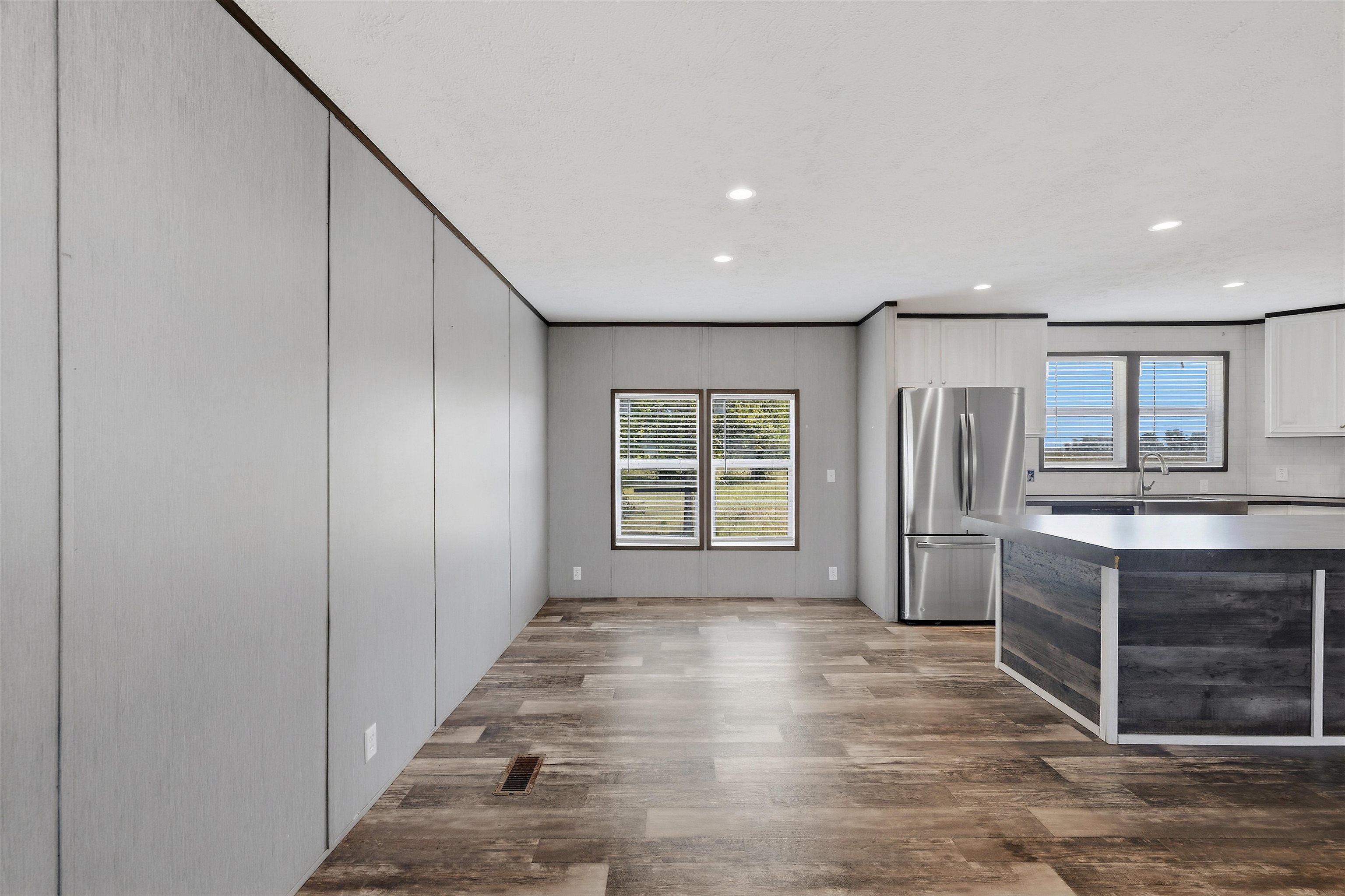 Open-concept living space with wood-finish flooring, recessed lighting, and stainless steel appliances