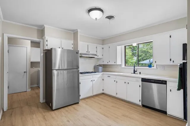 a kitchen with appliances a refrigerator a sink cabinets and wooden floor