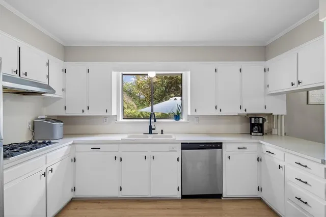 a kitchen with cabinets appliances a sink and a window